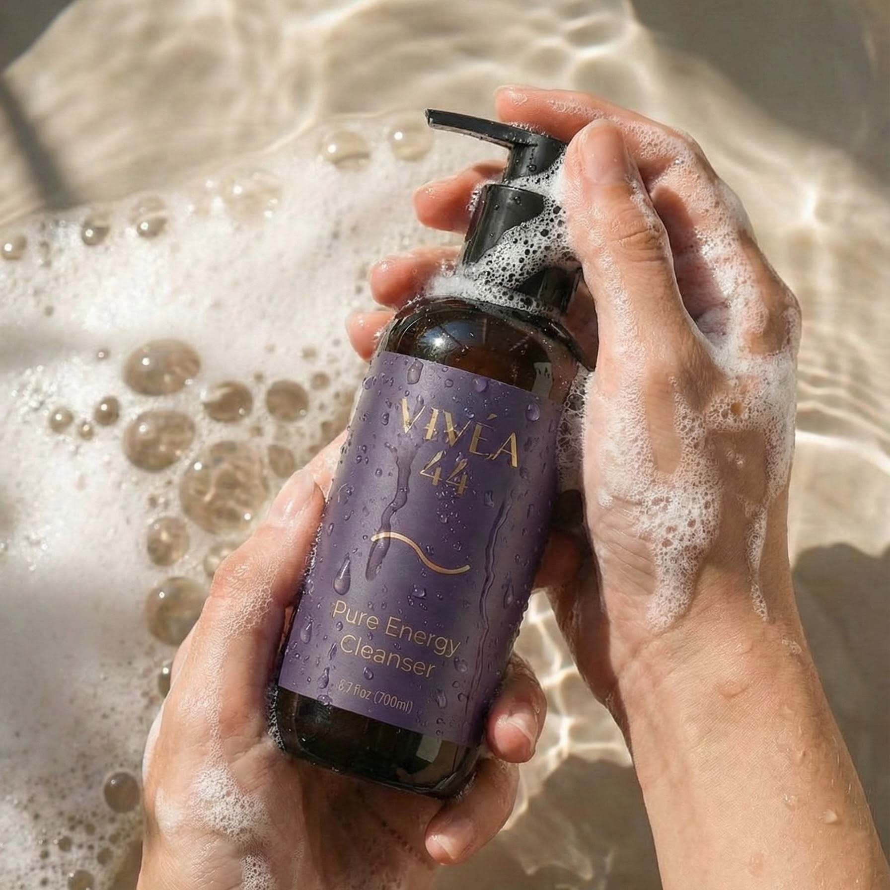 Person holding a Vivéa Pure Energy Cleanser bottle labeled with soap bubbles in the background