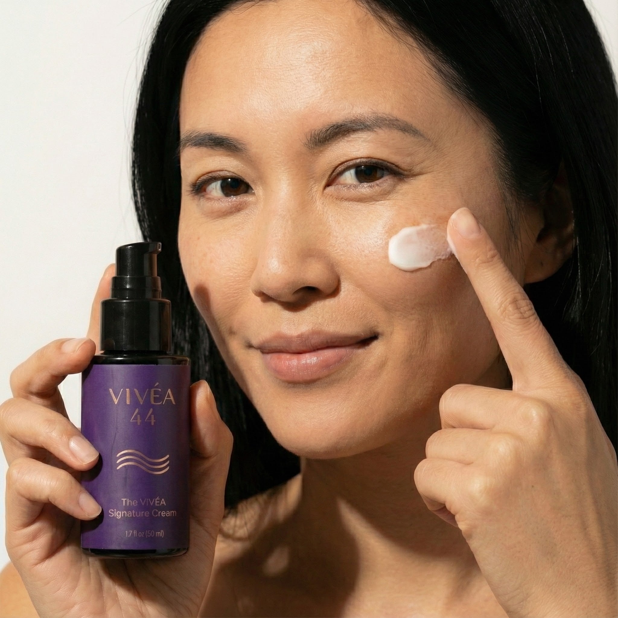 Woman applying cream to her face with a VIVEA 44 skincare product.