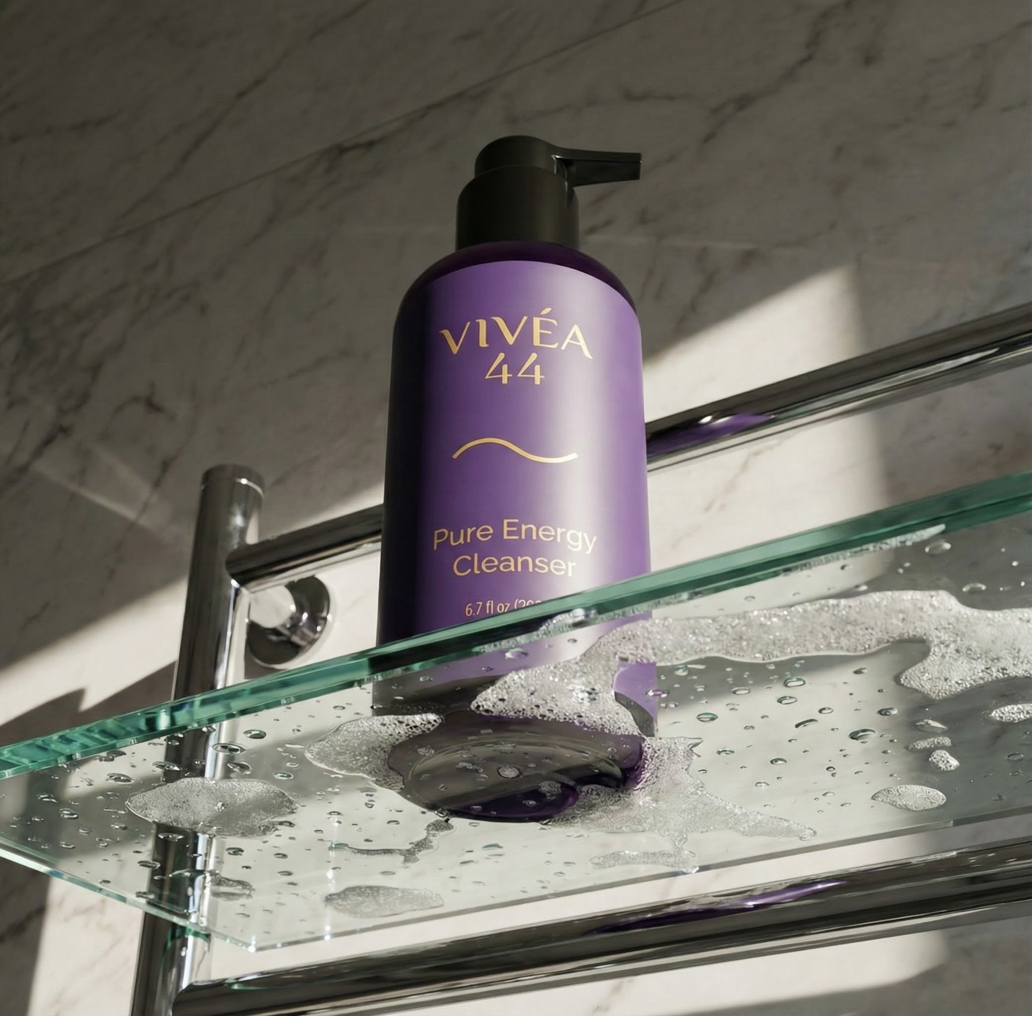 Vivea 44 Pure Energy Cleanser bottle on a glass shelf with marble wall background