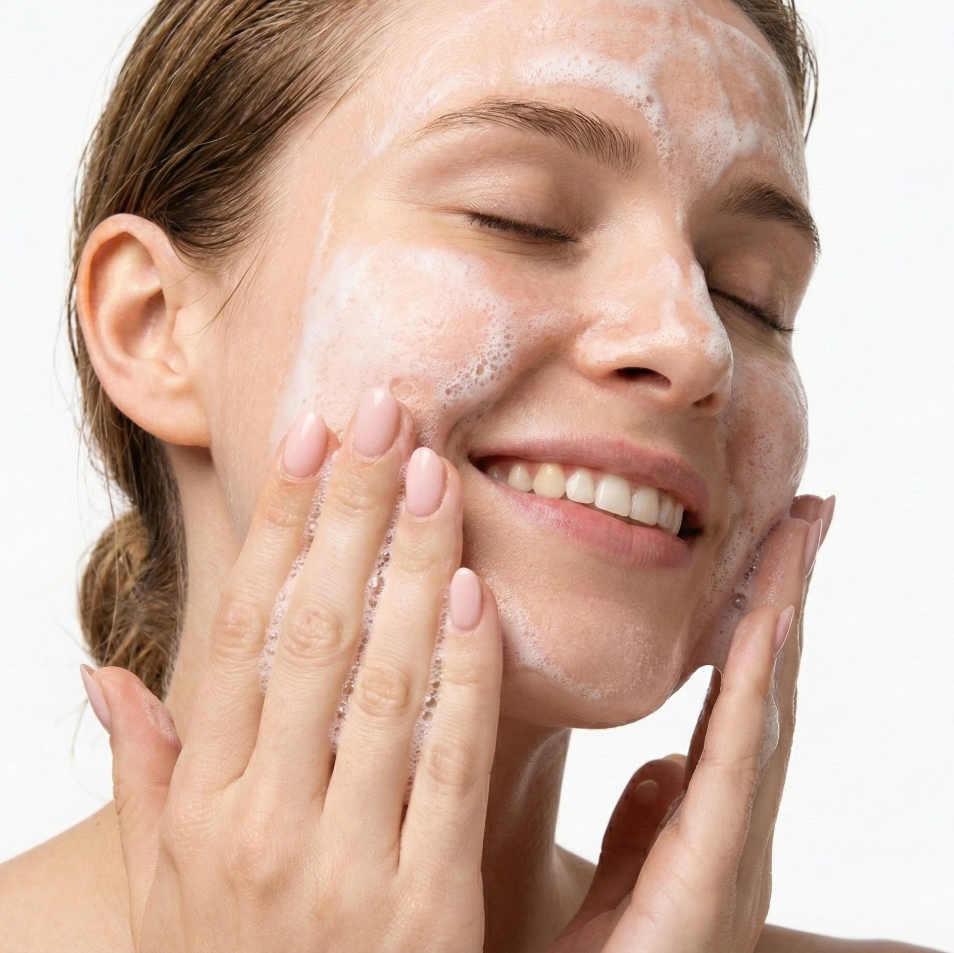 Woman applying a facial cleanser with a white background
